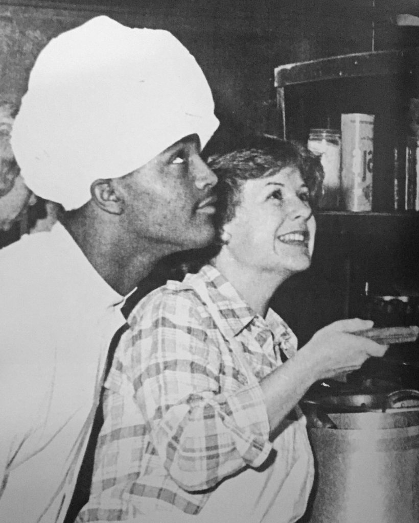 TRICKY FLIPS... Virginia Lyon shows Andre Smith a fancy cooking technique for the annual Cry-Slur Pancake Supper before the Homecoming football game.